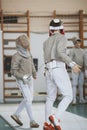 Two teenager fencers with swords on the fencing competition