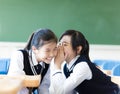 Two teenager girls gossiping in classroom