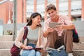 Two teenagers sitting on the university campus stairs, studying lessons and doing homework using a tablet. Classmates Royalty Free Stock Photo