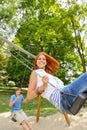 Two teenagers on swing playground in park