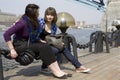 Two teens girl sitting on embankment.