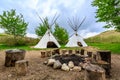 Two teepees are set up in a grassy field with a fire pit in the center Royalty Free Stock Photo