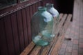 Two ten-liter glass jars stand on a bench in the garden