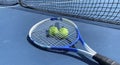 Two tennis balls with a racket on top on a blue tennis court Royalty Free Stock Photo