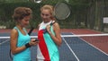 Two tennis girls discussing while sharing a smartphone Royalty Free Stock Photo