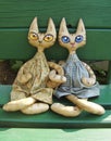 Two textile toy cats with big expressive eyes are sitting on a green bench on a sunny summer day Royalty Free Stock Photo