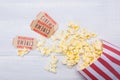 Two tickets to the cinema, along with a package of scattered popcorn, on a light, wooden background Royalty Free Stock Photo