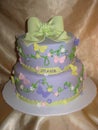 Two tier cake covered in purple fondant with butterflies and an elegant bow on top