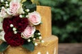 Two tiered white and gold wedding cake with red and pink roses and ruscus leaves Royalty Free Stock Photo