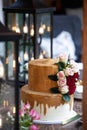 Two tiered white and gold wedding cake with red and pink roses and ruscus leaves Royalty Free Stock Photo