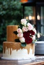 Two tiered white and gold wedding cake with red and pink roses and ruscus leaves Royalty Free Stock Photo