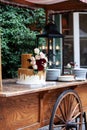 Two tiered white and gold wedding cake with red and pink roses and ruscus leaves on a wooden vintage cart Royalty Free Stock Photo