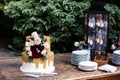 Two tiered white and gold wedding cake with red and pink roses and ruscus leaves on a wooden vintage cart Royalty Free Stock Photo