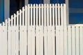 Two tiered white picket fence in front of a blue building