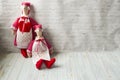 Two tilde dolls in red dresses, and white aprons, and in red kalpaks sit on a light background. Interior dolls. There is a place