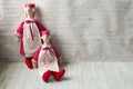 Two tilde dolls in red dresses, and white aprons, and in red kalpaks sit on a light background. Interior dolls. There is