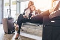 Two tired female tourists sleeping sitting on bench with baggage near them in waiting room in airport Royalty Free Stock Photo