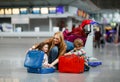 Two tired little kids, boy and girl, siblings and mother at the airport. Children, family traveling, going on vacation by plane