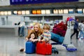 Two tired little kids, boy and girl, siblings and mother at the airport. Children, family traveling, going on vacation