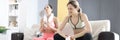 Two tired women are sitting on couch after fitness workout