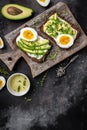 Two toasts with avocado, poached egg and microgreen on a dark background. diet or vegetarian food. vertical image. top view. place Royalty Free Stock Photo