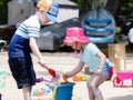 Two Toddlers, a Boy & a Girl, Dressed with Good Sun Protection, Play on a Sandy Beach Building Sand Castles Royalty Free Stock Photo