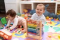 Two toddlers playing with abacus sitting on floor at kindergarten Royalty Free Stock Photo