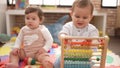 Two toddlers playing with abacus sitting on floor at kindergarten Royalty Free Stock Photo