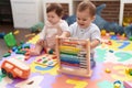 Two toddlers playing with abacus sitting on floor at kindergarten Royalty Free Stock Photo