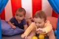 Two toddlers playing with balls sitting inside circus tent at home