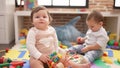 Two toddlers playing with toys sitting on floor at kindergarten Royalty Free Stock Photo