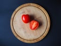 Two tomatoes on the round wooden cutting board top view Royalty Free Stock Photo