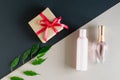 on a two-tone gray-beige background a gift with a red ribbon, a pink cosmetic bottle, a bottle of perfume . Royalty Free Stock Photo