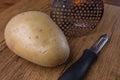 A potatoe with a peeler and a tool to crushed potatoe on wooden Royalty Free Stock Photo