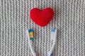 Two toothbrushes and a red heart on a knitted gray background. Love, family concept and valentines day, two lovers live together. Royalty Free Stock Photo