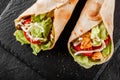 Two Tortilla wraps with grilled chicken fillet, fresh vegetables and salad on black stone background. Healthy snack or take-away Royalty Free Stock Photo