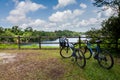Two Tourist Bikes Parked By The Tropical Lake Ketam Quarry On Pulau Ubin Island, Singapore With Rainforest View, Wooden Fence