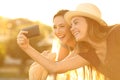 Two tourist friends taking selfies in hotel balcony