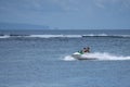 Two tourist girls drive water scooter very fast in shallow water close to Sanur beach in Bali. Sanur, Indonesia - January 9, 2020