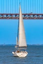 Two tourist recreation sailboats sailing on the Tagus River with the red steel 25 de Abril suspension bridge above them with car Royalty Free Stock Photo