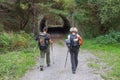 Two tourists in front of an arch in a forest view from the back