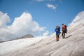 Two tourists, a man and a woman with backpacks and cats on their feet, stand on the ice in the background of the Royalty Free Stock Photo