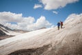 Two tourists, a man and a woman with backpacks and cats on their feet, stand on the ice in the background of the Royalty Free Stock Photo