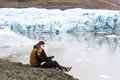 Two tourists are sitting near the glacier iceberg in Iceland Royalty Free Stock Photo