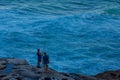 Two tourists standing with fishing rod in hand on the edge of rock cliff at Tamarama beach