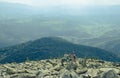 Two tourists on the top of a mountain in the Carpathians build a figure of stones against the backdrop of mountain ranges