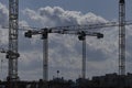 Two tower cranes have crossed their arrows and are lifting loads Royalty Free Stock Photo