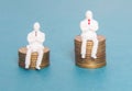 Two toy people are sitting on money dollars cents concept of earnings of a worker and a boss. Salary of the subordinate Royalty Free Stock Photo