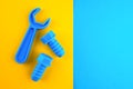 Two toy plastic bolts and wrench of blue color on a yellow-blue background.