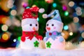 Two toy snowmen under Christmas tree on background bright bokeh _ Royalty Free Stock Photo